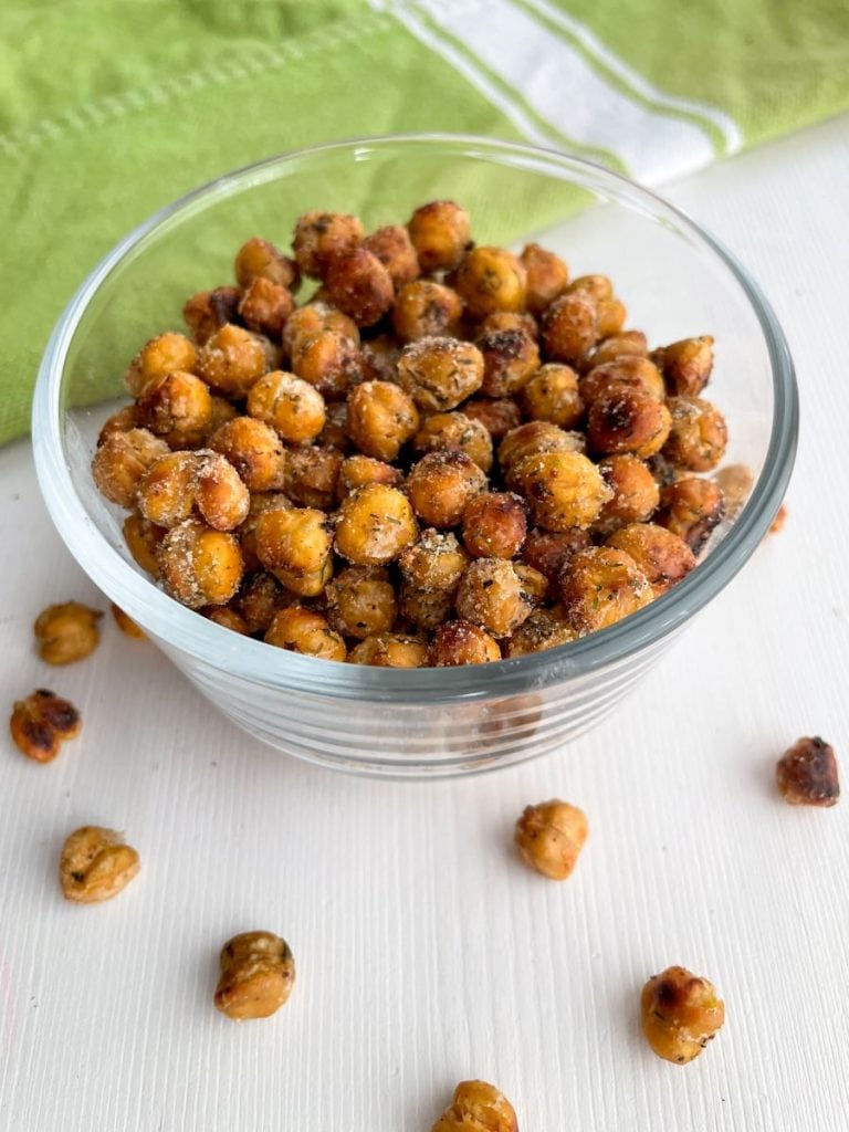 bowl of ranch dill flavored crispy chickpeas in glass bowl on top of green towel 