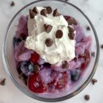 bowl of frozen fruit ice cream topped with whipped topping and mini chocolate chips