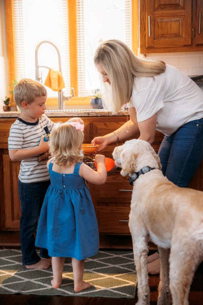 Mom serving kids a bowl of grapes while dog looks on