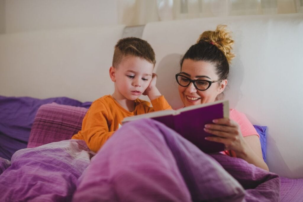 Mom and son reading in bed during night routine is one way you can fall asleep quicker